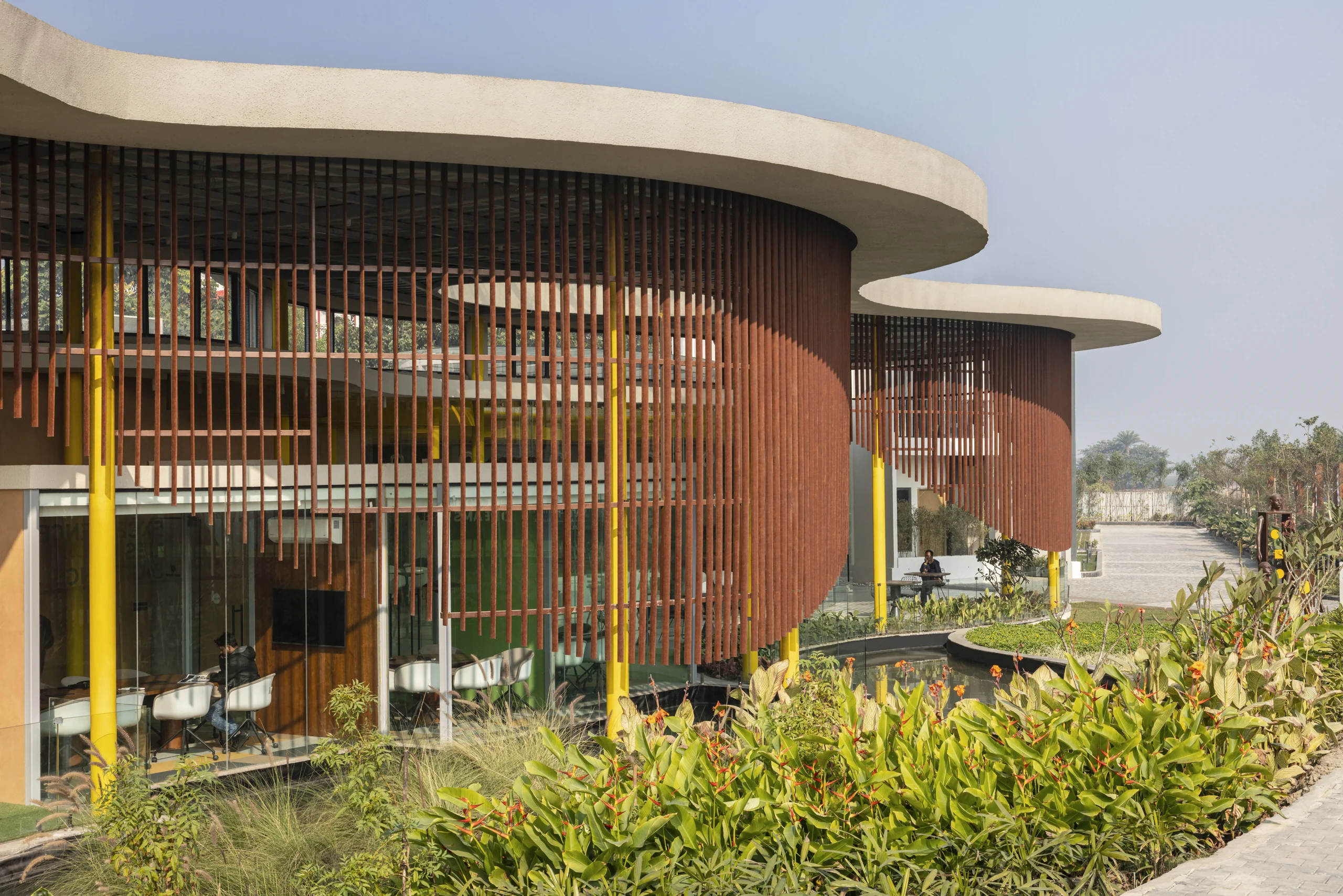 Curved facade with vertical timber fins and landscaped approach